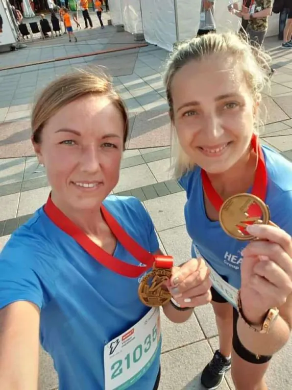 Dvi besišypsančios moterys su maratono medaliais